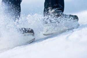 hockey skates sliding to a stop spraying snow everywhere.